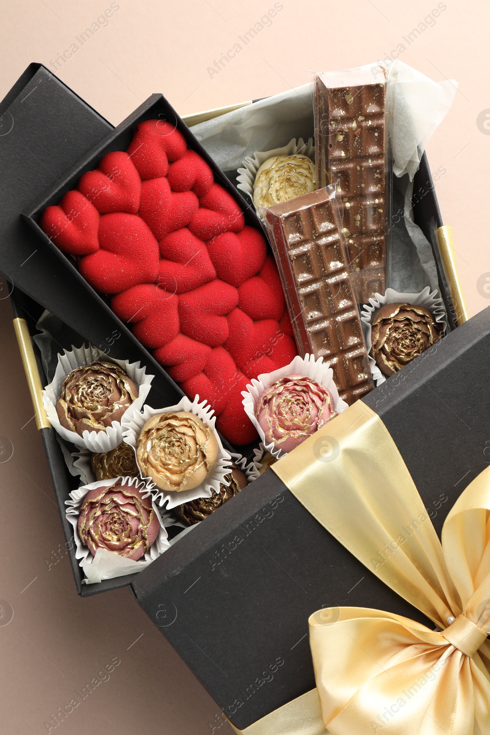 Photo of Different delicious chocolate sweets in box on beige background, top view