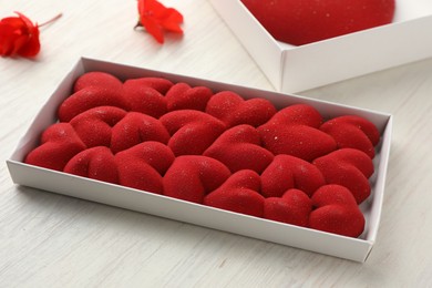 Photo of Chocolate bar decorated with hearts on light wooden background, closeup