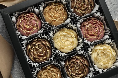 Photo of Delicious flower shaped chocolate bonbons in box on grey background, closeup