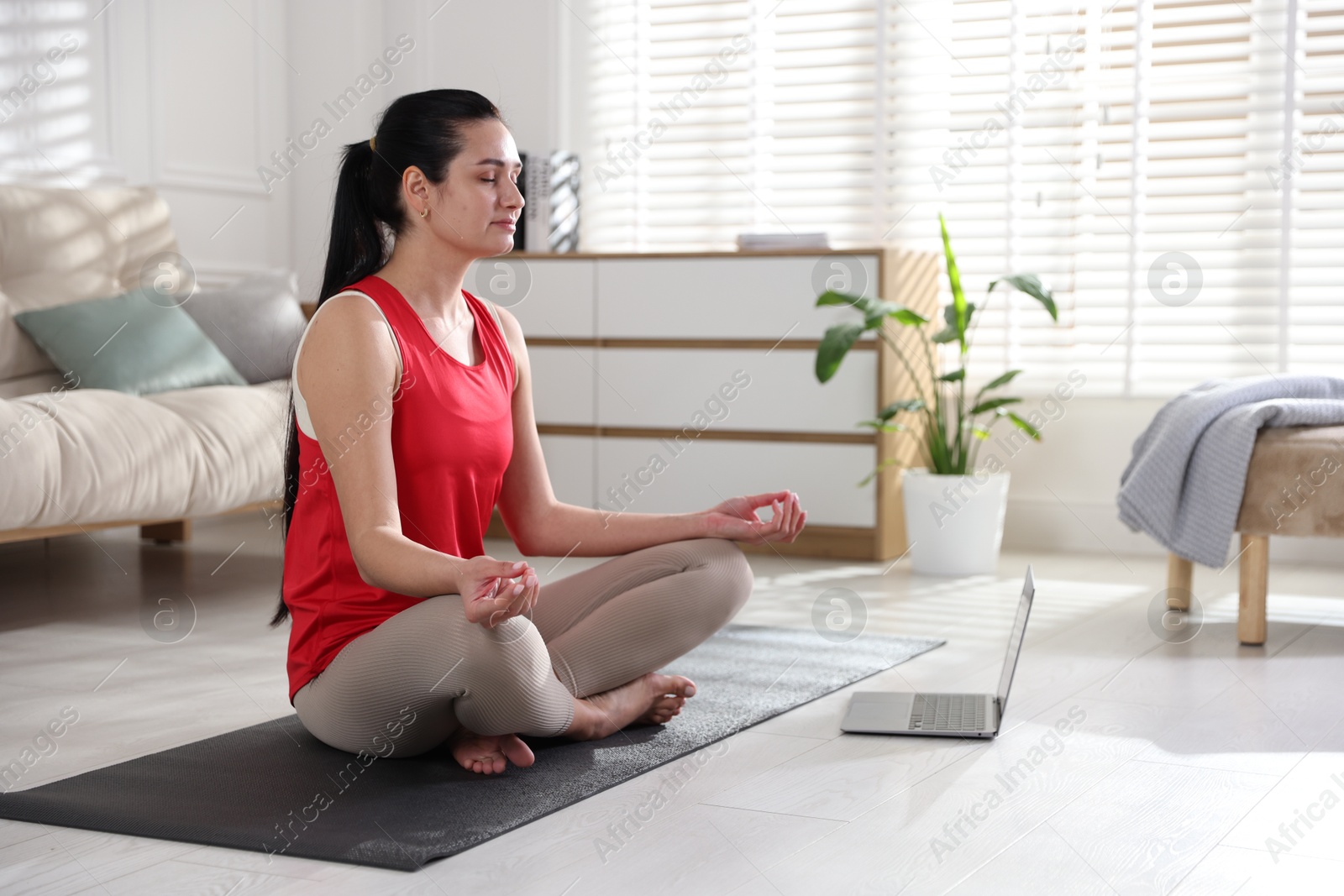 Photo of Woman with laptop meditating on floor at home. Space for text