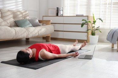 Photo of Woman with laptop meditating on floor at home