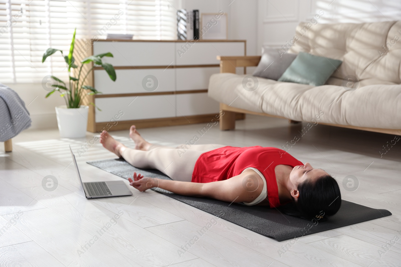 Photo of Woman with laptop meditating on floor at home