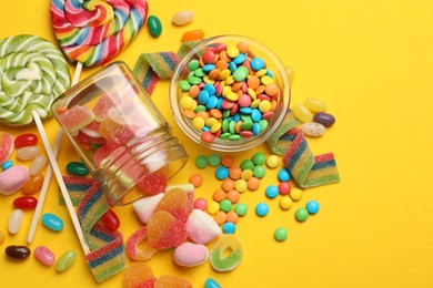 Photo of Many different tasty candies on yellow background, flat lay