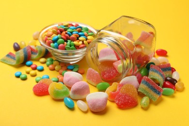 Photo of Many different tasty candies on yellow background, closeup