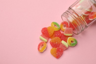 Photo of Many different tasty candies and jar on pink background, flat lay. Space for text