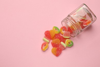 Photo of Many different tasty candies and jar on pink background, flat lay. Space for text