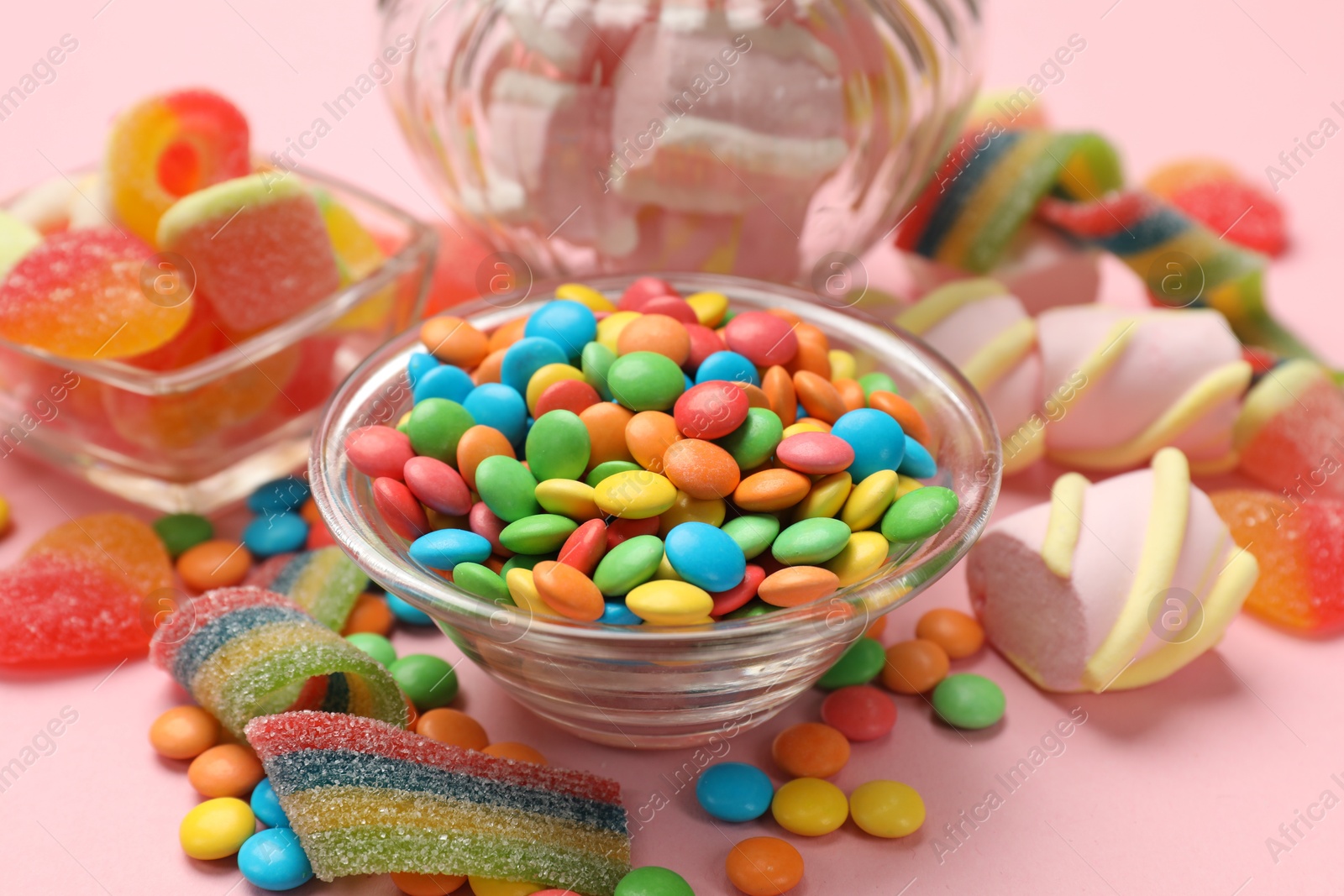 Photo of Many different tasty candies on pink background, closeup