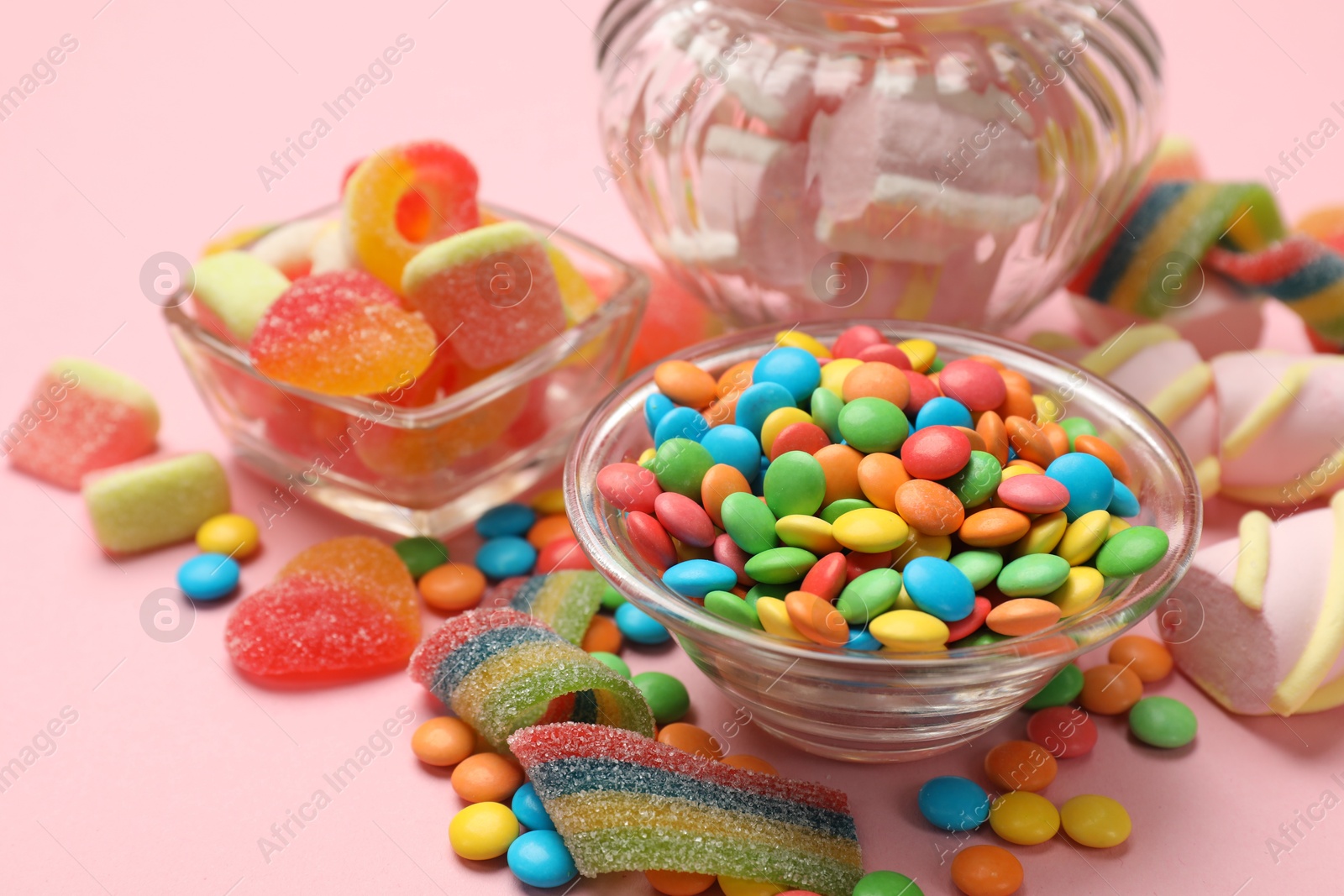 Photo of Many different tasty candies on pink background, closeup