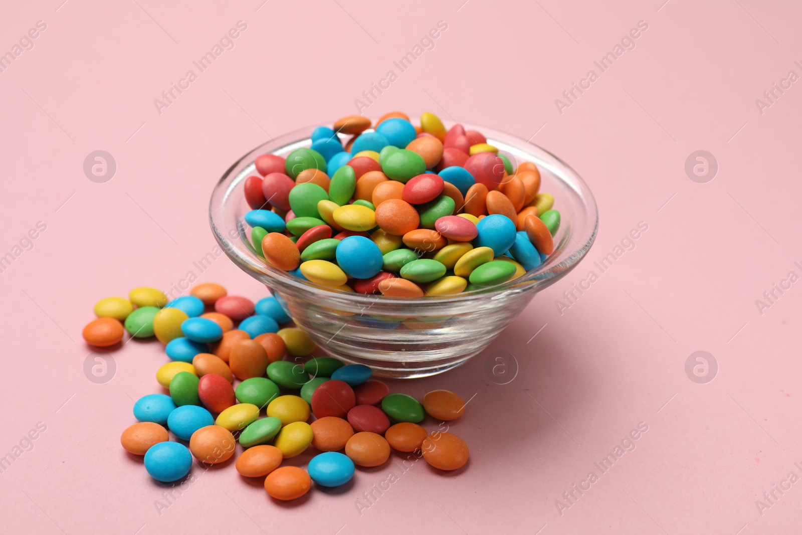 Photo of Tasty candies in bowl on pink background, closeup