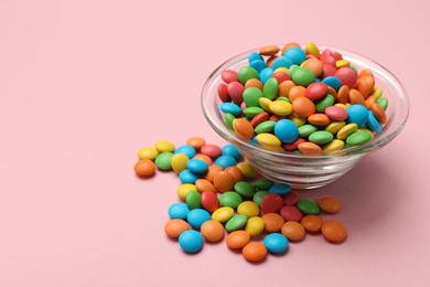 Photo of Tasty candies in bowl on pink background, closeup. Space for text