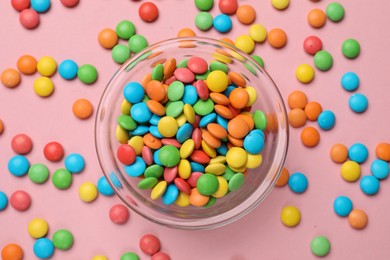 Photo of Tasty candies in bowl on pink background, top view