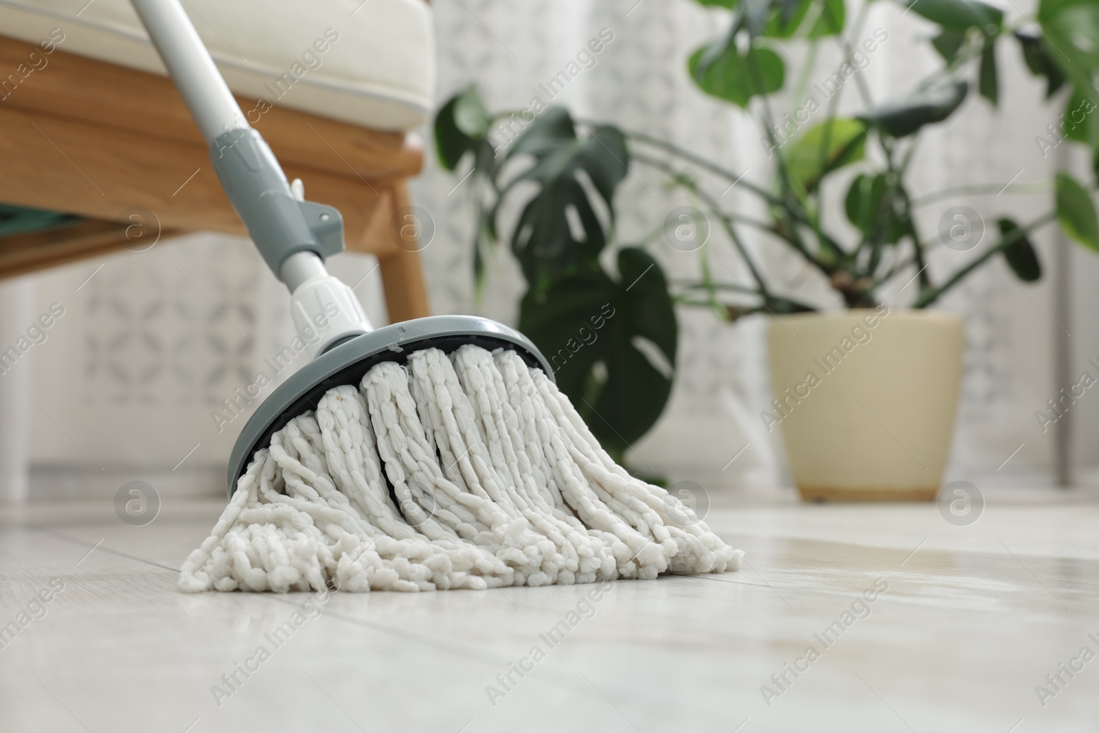 Photo of String mop on floor indoors. Cleaning equipment