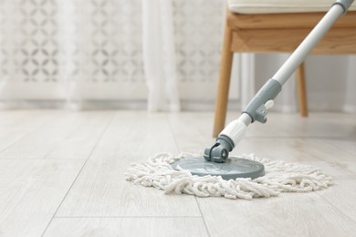 Photo of String mop on floor indoors, space for text. Cleaning equipment