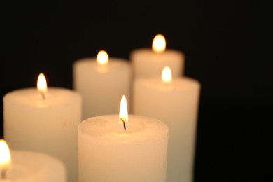 Photo of Many burning candles in darkness, closeup view