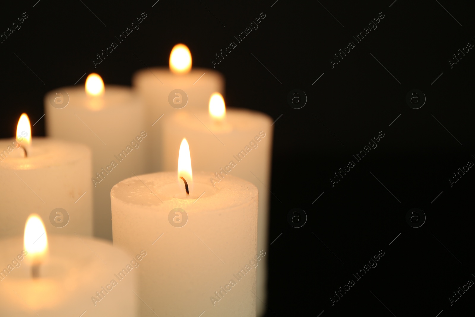 Photo of Many burning candles in darkness, closeup. Space for text