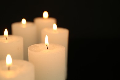 Photo of Many burning candles in darkness, closeup. Space for text