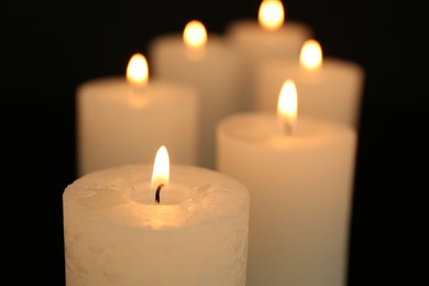 Photo of Many burning candles in darkness, closeup view