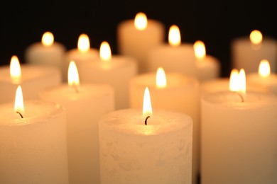 Photo of Many burning candles in darkness, closeup view