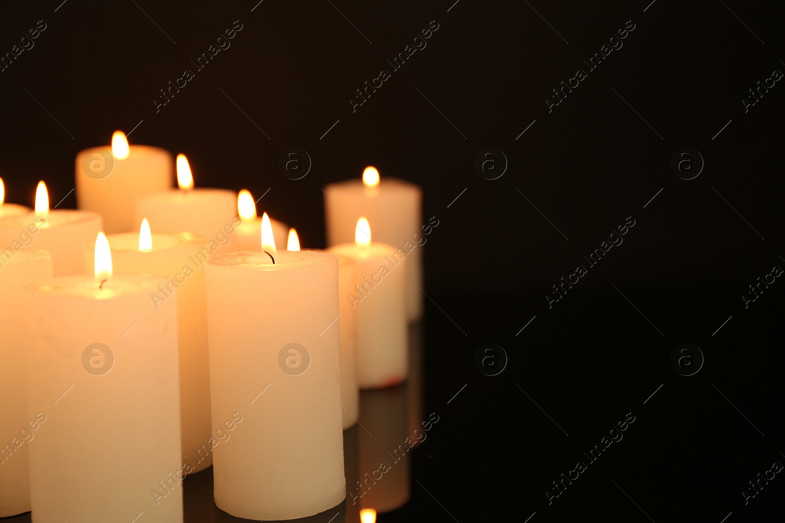 Photo of Many burning candles in darkness, closeup. Space for text