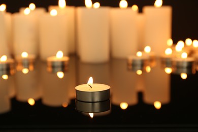 Photo of Burning candles on dark mirror surface, closeup