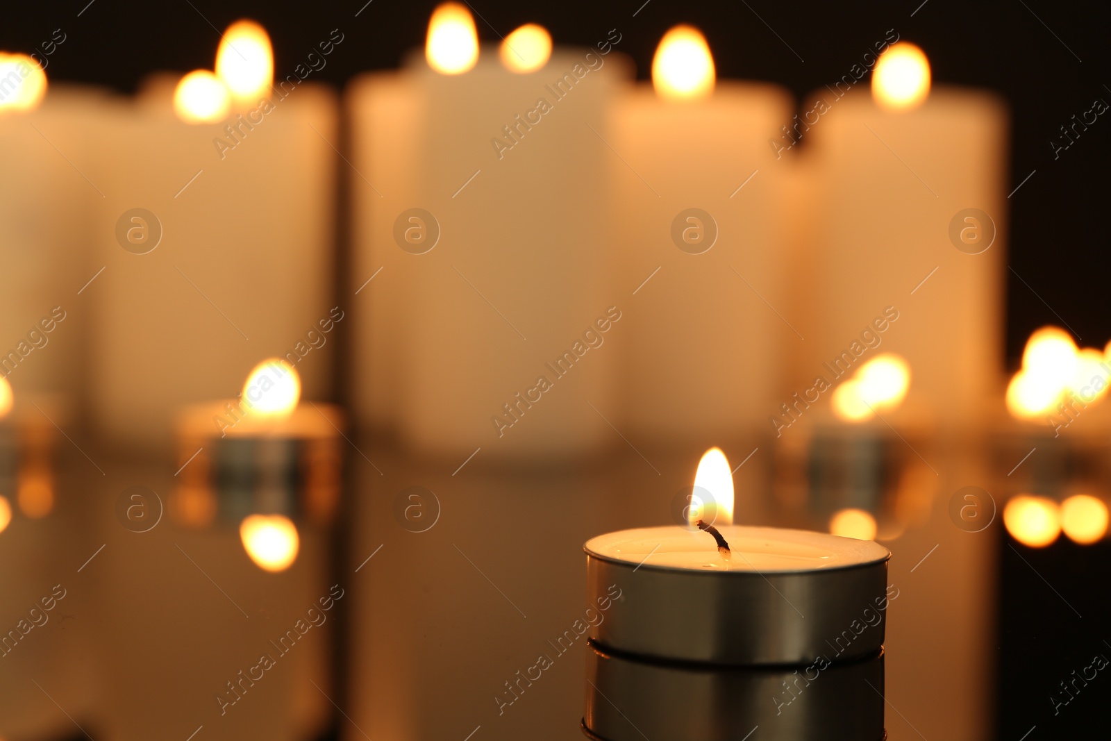 Photo of Burning candles on dark mirror surface, closeup. Space for text