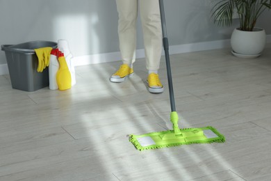 Photo of Woman cleaning floor with microfiber mop indoors, closeup