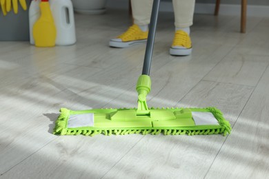 Photo of Woman cleaning floor with microfiber mop indoors, closeup