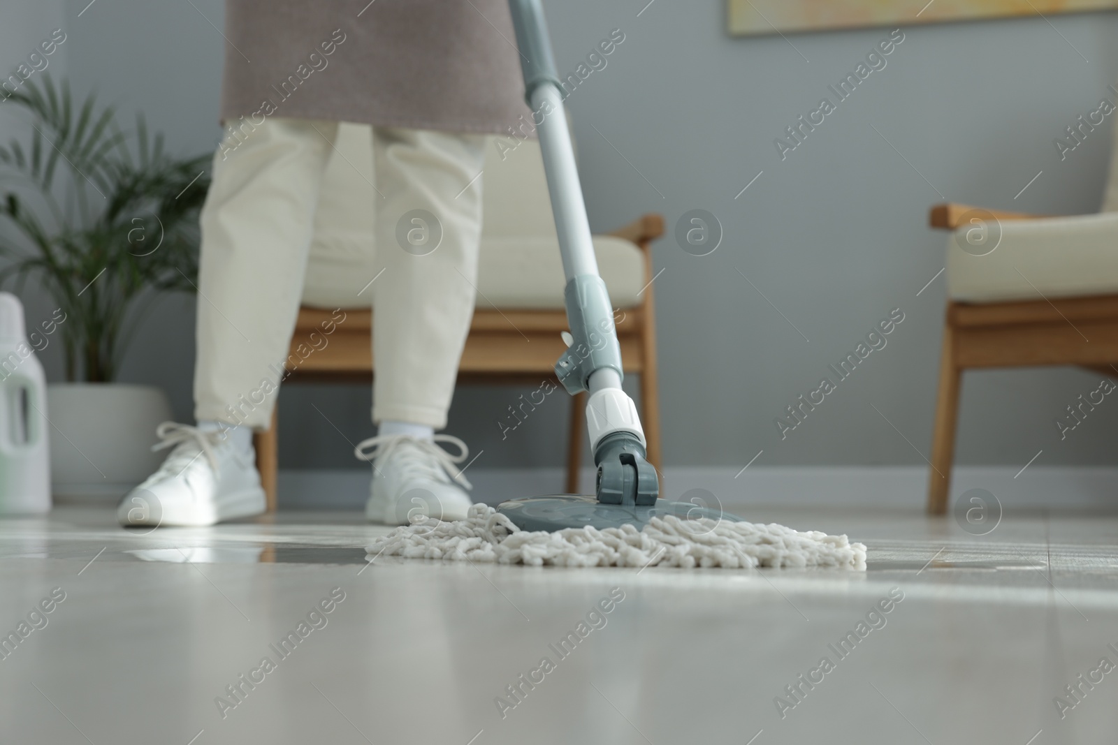 Photo of Woman cleaning floor with string mop indoors, closeup