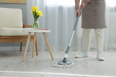 Photo of Woman cleaning floor with string mop indoors, closeup