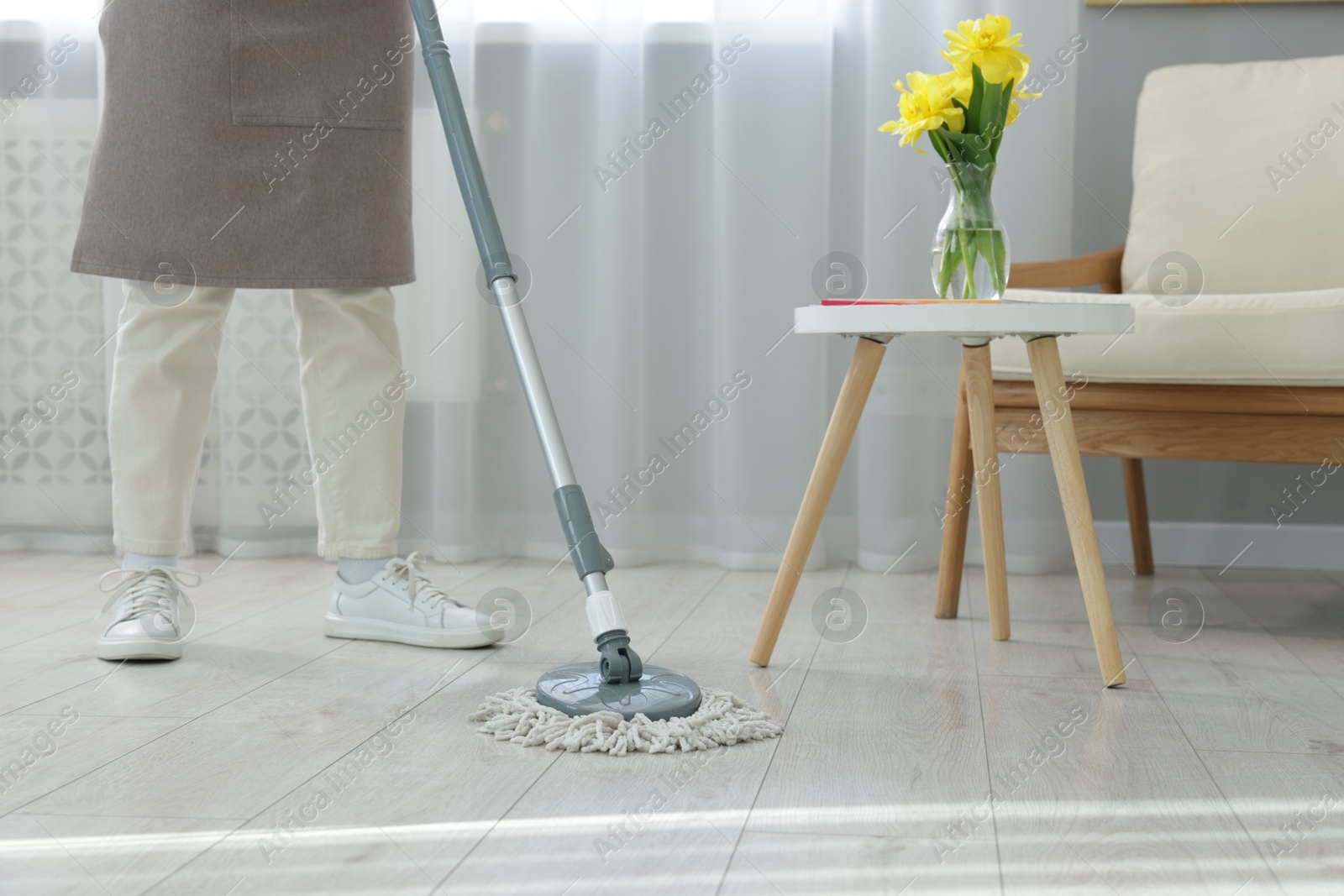 Photo of Woman cleaning floor with string mop indoors, closeup