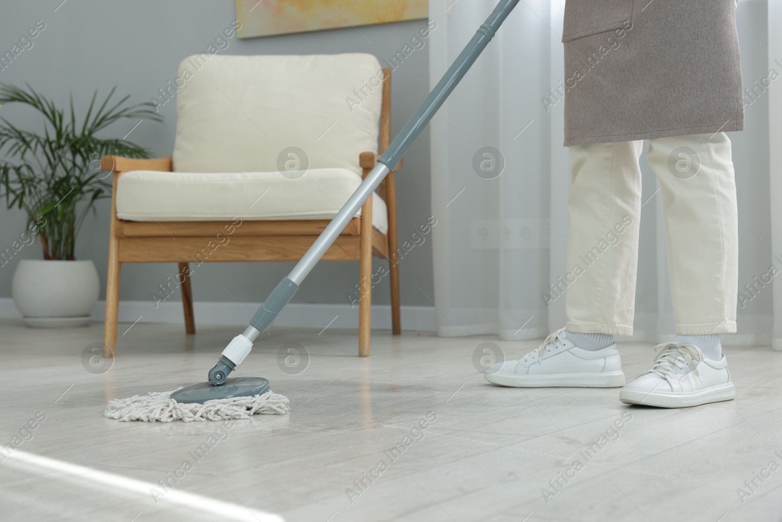 Photo of Woman cleaning floor with string mop indoors, closeup