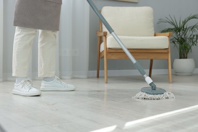 Photo of Woman cleaning floor with string mop indoors, closeup