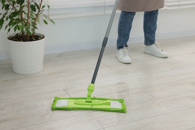 Photo of Woman cleaning floor with microfiber mop indoors, closeup