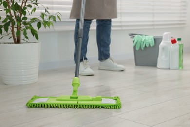 Photo of Woman cleaning floor with microfiber mop indoors, closeup