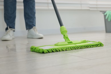 Photo of Woman cleaning floor with microfiber mop indoors, closeup