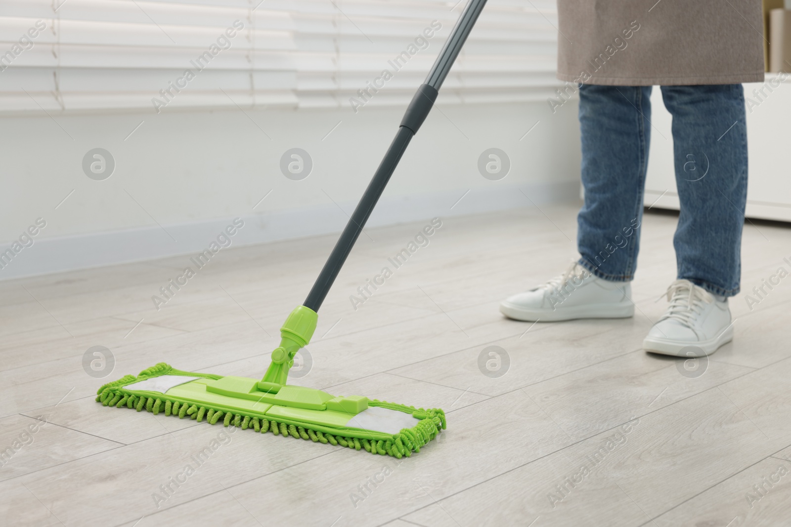 Photo of Woman cleaning floor with microfiber mop indoors, closeup