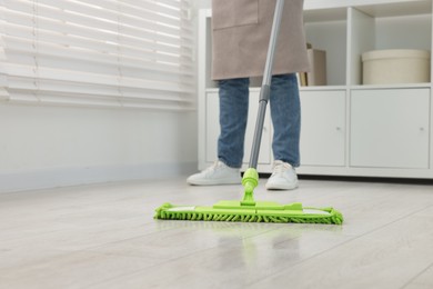 Photo of Woman cleaning floor with microfiber mop indoors, closeup