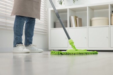 Photo of Woman cleaning floor with microfiber mop indoors, closeup