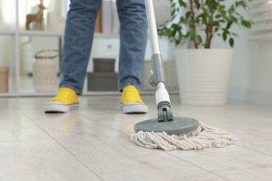 Photo of Woman cleaning floor with string mop indoors, closeup