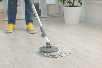 Photo of Woman cleaning floor with string mop indoors, closeup