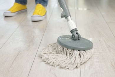 Photo of Woman cleaning floor with string mop indoors, closeup