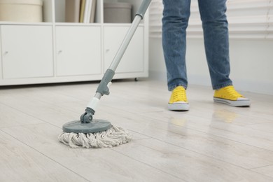 Photo of Woman cleaning floor with string mop indoors, closeup