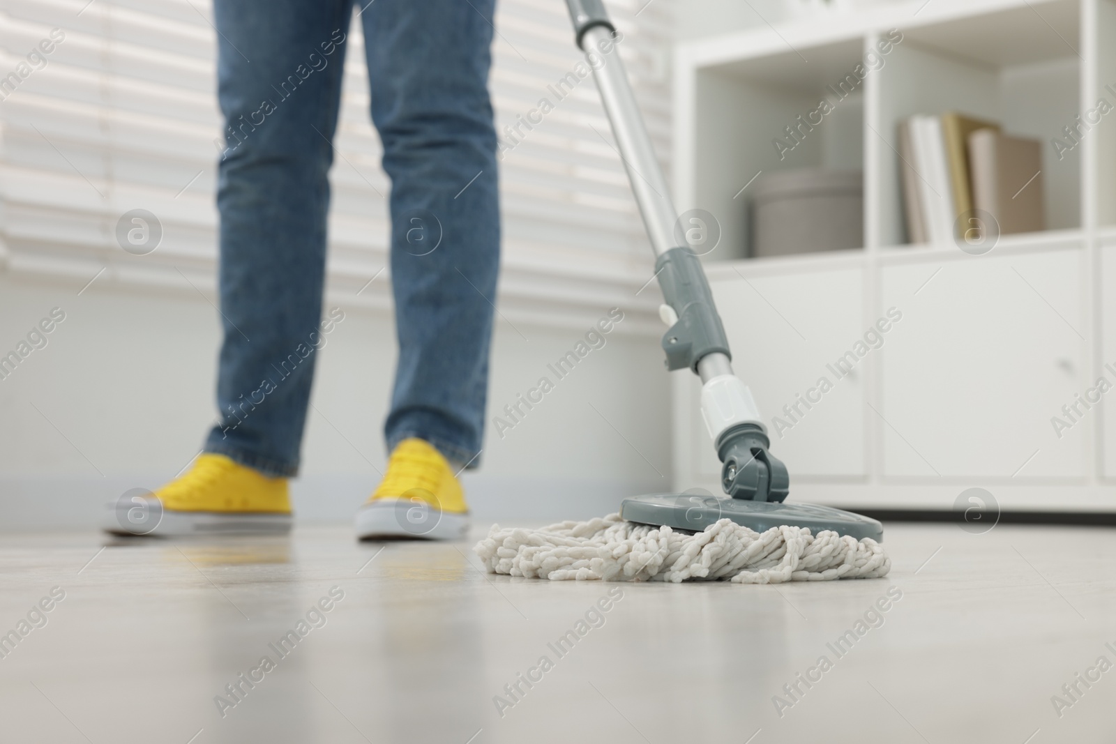 Photo of Woman cleaning floor with string mop indoors, closeup