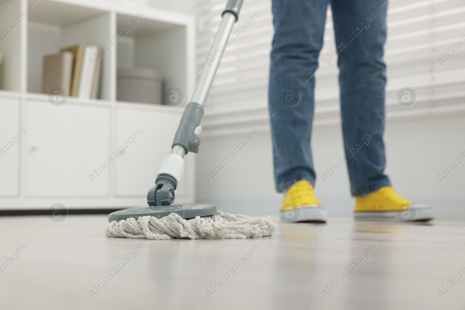 Photo of Woman cleaning floor with string mop indoors, closeup