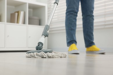 Photo of Woman cleaning floor with string mop indoors, closeup