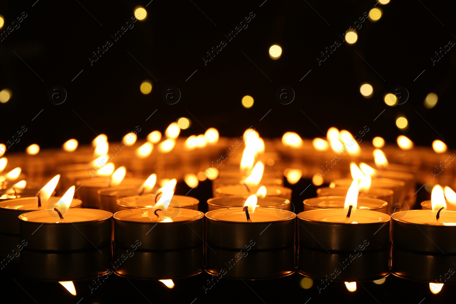 Photo of Burning candles in darkness, closeup. Bokeh effect