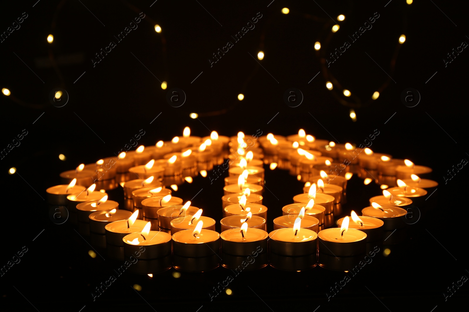 Photo of Many burning candles in darkness. Bokeh effect