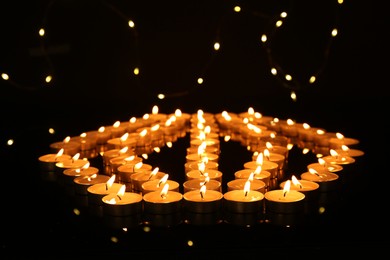 Photo of Many burning candles in darkness. Bokeh effect