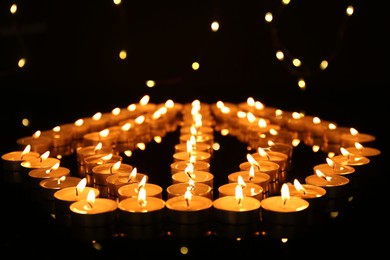 Photo of Many burning candles in darkness, closeup. Bokeh effect