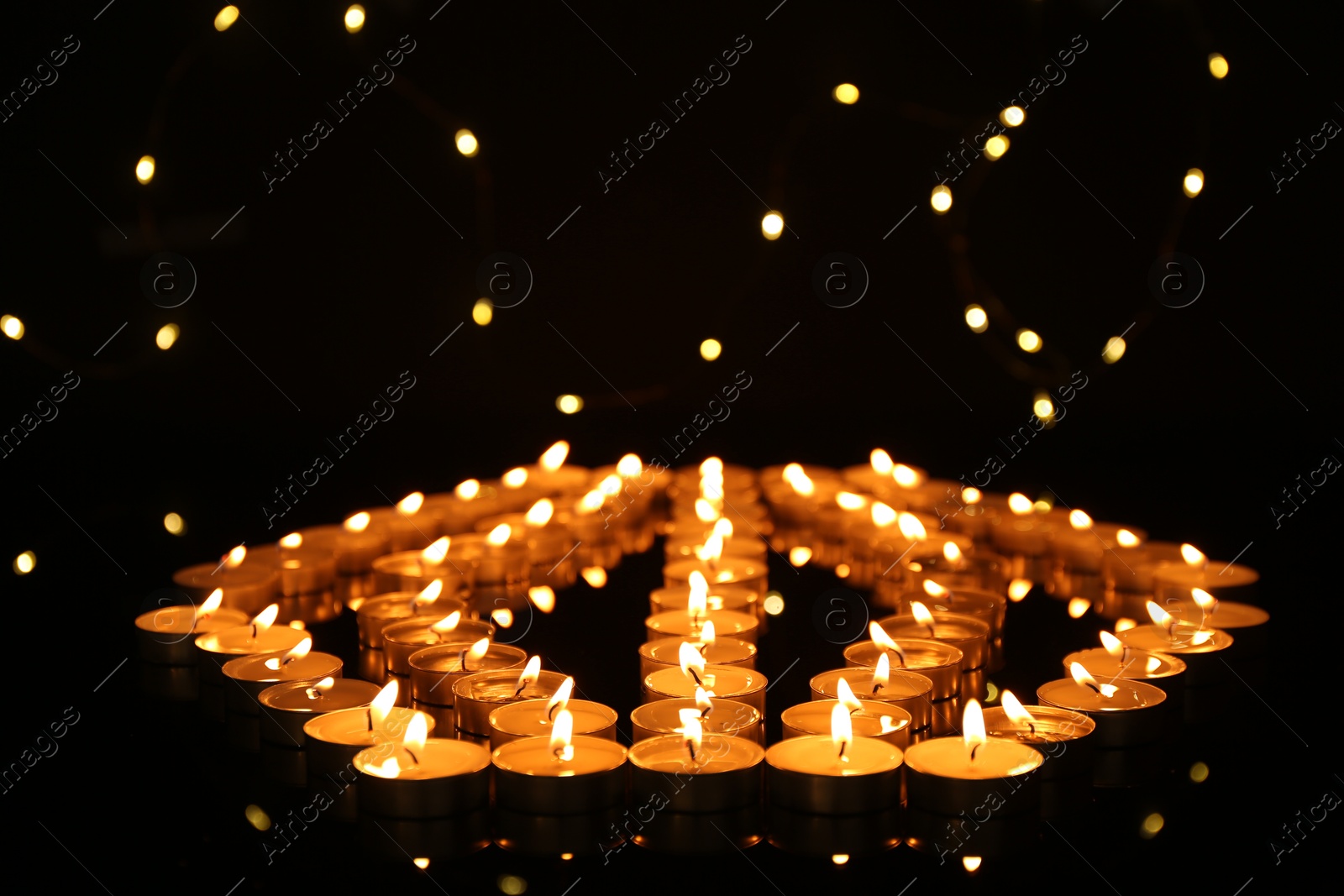 Photo of Many burning candles in darkness. Bokeh effect